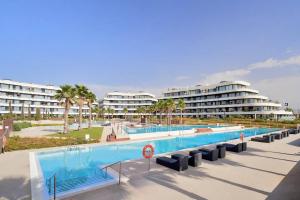 a large swimming pool with two apartment buildings in the background at Luxury complex beachfront apartment with gym and large terrace in Torremolinos