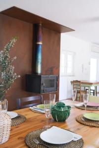 Una mesa de madera con platos y copas de vino encima. en The ONE - Country House, en Grândola