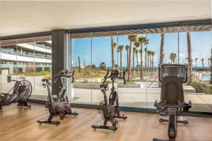 un gimnasio con 5 bicicletas estáticas en un edificio con palmeras en Luxury complex beachfront apartment with gym and large terrace, en Torremolinos