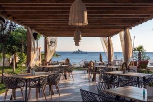 a restaurant with tables and chairs and a boat in the water at Sea & Stone Villas in Koundouros