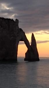 uma grande formação rochosa no oceano com um pôr-do-sol em Villa Panorama, vue mer et falaises d exception em Étretat