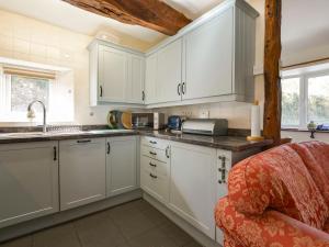a kitchen with white cabinets and a sink at The Cottage in Moretonhampstead