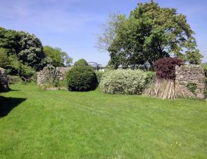 a yard with green grass and trees and bushes at The Cottage in Moretonhampstead