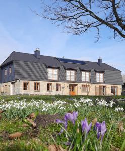ein großes Haus mit weißen Blumen davor in der Unterkunft Hof Ruemland Ferienwohnungen in Hollingstedt