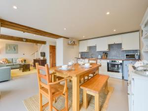 cocina y sala de estar con mesa de madera y sillas en The Bolthole, en Okehampton