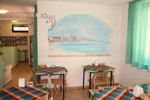 a room with tables and chairs and a painting on the wall at Hotel Alguer in Alghero