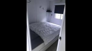 a small bed in a small room with a window at Chalet 4-6 personen op 5* camping Terspegelt in Eersel