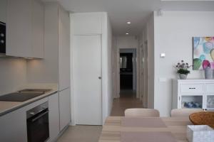 a kitchen with white cabinets and a living room at Luxury complex beachfront apartment with gym and large terrace in Torremolinos