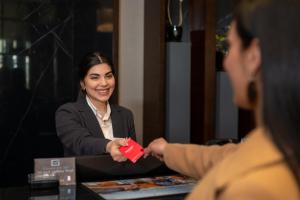 a woman handing a red item to a woman at a table at Ramada by Wyndham Erbil Gulan Street in Erbil