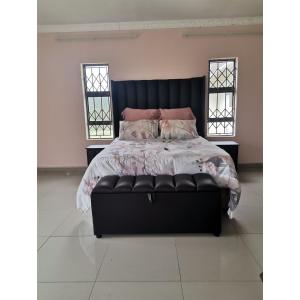a bedroom with a black bed with pink pillows at Phakathi Lifestyle Village Umnini in Amanzimtoti
