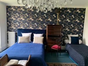 ein Schlafzimmer mit einem blauen Bett, einer Kommode und einem Stuhl in der Unterkunft Domaine de Ris in Ris-Orangis