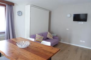 a living room with a table and a purple couch at Casa Barcelli Sport & Family Apartments in Nago-Torbole
