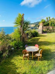 una mesa y sillas en la hierba cerca del océano en Beach Shack Apartment, en Shanklin