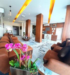 a lobby with brown couches and flowers in the middle at Grand Orchid Hotel Apartment in Duqm
