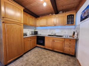 a kitchen with wooden cabinets and a black dishwasher at Cottage Zoja in Bohinjska Bistrica