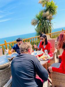 a group of people sitting at a table eating food at Beach Shack Apartment in Shanklin