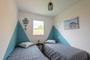 2 camas en un dormitorio con paredes azules y blancas en Maison avec jacuzzi, en Biscarrosse