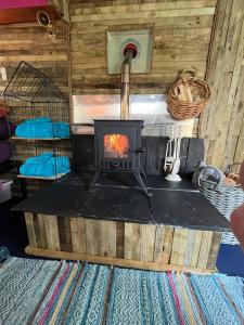 a fireplace in the front of a tiny house at Budget stay, in lovely private setting with rustic charm, log burner, fire pit, campers kitchen & Eco Loo NO BEDDING SUPPLIED in Narberth