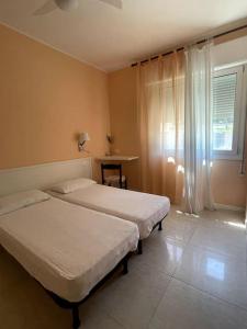 una camera con due letti e una finestra con tende di Bungalows Alloggi Angiolin Ketty a Cavallino-Treporti