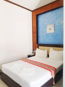 a bedroom with a bed with a large painting on the wall at Palm Inn in Khok Kloi