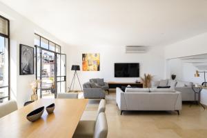 een woonkamer met witte meubels en een tafel bij Amazing Duplex with 2 Terraces in City Center by FeelHome in Tel Aviv