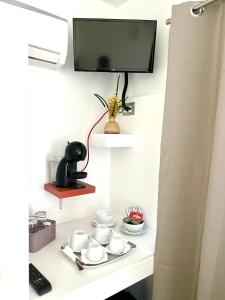 TV en una pared sobre una mesa blanca con platos en La Casa Particular, en Bari