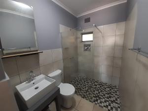 a bathroom with a white toilet and a sink at Honeysuckle Manor in Richards Bay