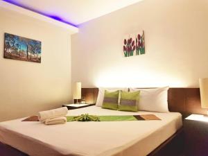 a bedroom with a large white bed with two lamps at Palm Inn in Khok Kloi