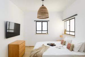 a white bedroom with a bed and a tv at Amazing Duplex with 2 Terraces in City Center by FeelHome in Tel Aviv