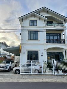 a white house with two cars parked in front of it at Ánh Vân Villa hotel in Da Lat
