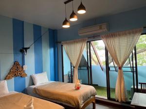 2 letti in una camera con pareti e finestre blu di Retro At Phra Sing Guest House a Chiang Mai