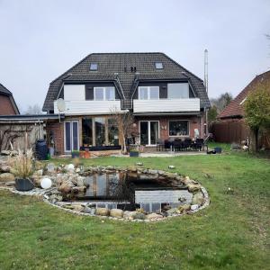 ein Haus mit einem Teich im Hof in der Unterkunft Im Heidedorf Haus to Baben in Cuxhaven