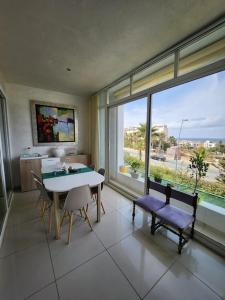 une salle à manger avec une table, des chaises et une grande fenêtre dans l'établissement Melrose Beach - Apartment with a beach view, à Dar Bouazza