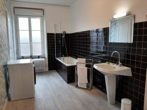 een zwart betegelde badkamer met een wastafel en een bad bij Bulle d'Ardenne in Charleville-Mézières +19 foto's
