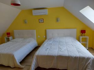 2 Betten in einem Schlafzimmer mit gelber Wand in der Unterkunft le four à pain in Faverolles