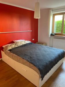uma cama num quarto com uma parede vermelha em Casa dei sogni em Valdaora