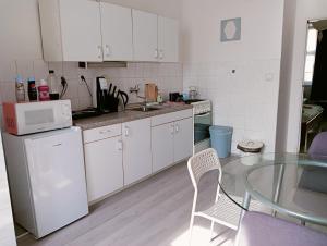 uma cozinha com armários brancos e uma mesa de vidro em Apartmán Hybešova em Brno