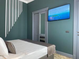 um quarto com uma cama e uma televisão de ecrã plano na parede em Teatro Rooms Hotel em Baku