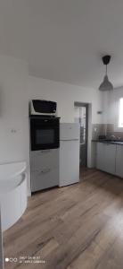 a white kitchen with a stove and a wooden floor at Appartement 4 personnes, garage privé, balcon in Saint-Étienne