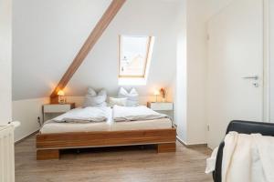 Un dormitorio con una cama con sábanas blancas y una ventana. en Strandpark-Grossenbrode-Haus-Meerblick-Wohnung-16, en Großenbrode