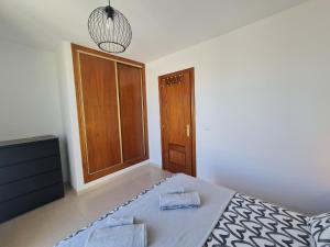 1 dormitorio con 1 cama y puerta de madera en We Fuerteventura, en Caleta de Fuste