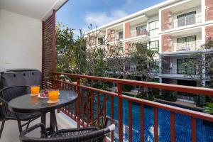 balcón con mesa, sillas y piscina en The Title Rawai West Wing Pool View Suite en Rawai Beach