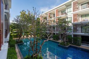 an apartment building with a swimming pool and trees at The Title Rawai West Wing Pool View Suite in Rawai Beach