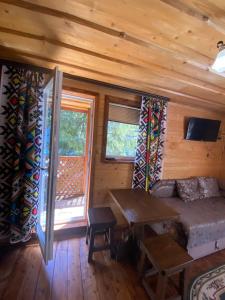 una sala de estar con sofá y mesa en una cabaña en Сімейний номер 2 Садиба У Ані, en Synevyrsʼka Polyana