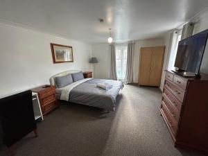 a bedroom with a bed and a dresser and a television at Mannys Apartment - Nice & Cozy 4Bed Flagship Lodge in Sittingbourne