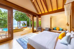a bedroom with a bed and a view of the ocean at Furaveri Maldives - COMPLIMENTARY ROUND-TRIP SEAPLANE TRANSFER for two for a minimum of 5 nights or more from May 1st to October 31st, 2025 in Raa Atoll