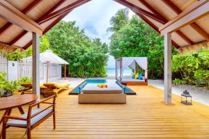 een buitenterras met een bed en een zwembad bij Furaveri Maldives in Raa Atol