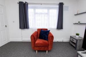 - Silla naranja con almohada azul en la habitación en K Suites - Ely Road, en Arksey