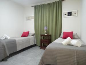 1 dormitorio con 2 camas y almohadas rojas y blancas en Casa Camino a Las Termas en San Salvador de Jujuy