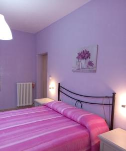 een slaapkamer met een bed met roze lakens en paarse muren bij nAnA' in Orsogna